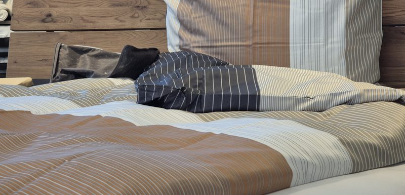Bezogenes Bett mit gestreifter Bettwäsche in Beige und Dunkelblau